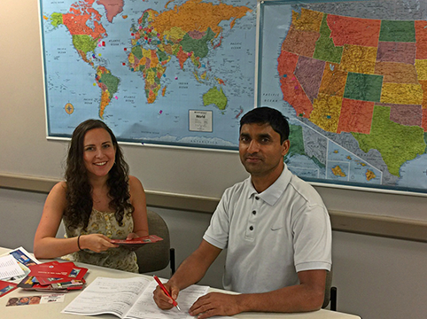 A man and a woman sitting at a table with maps on the wall behind them.